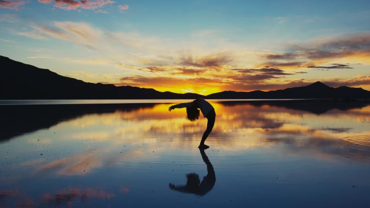 Sunset on a beach with someone doing a back bend